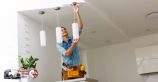 A man holding a light fixture next to two of the same fixtures in a room